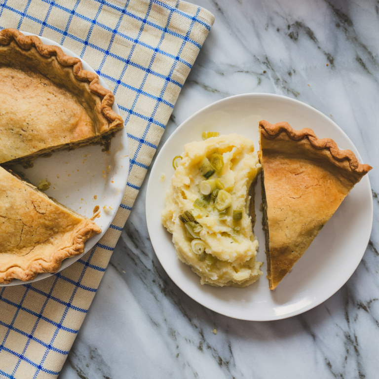 savory pie on a white plate with checkered blue and white napkin underneath